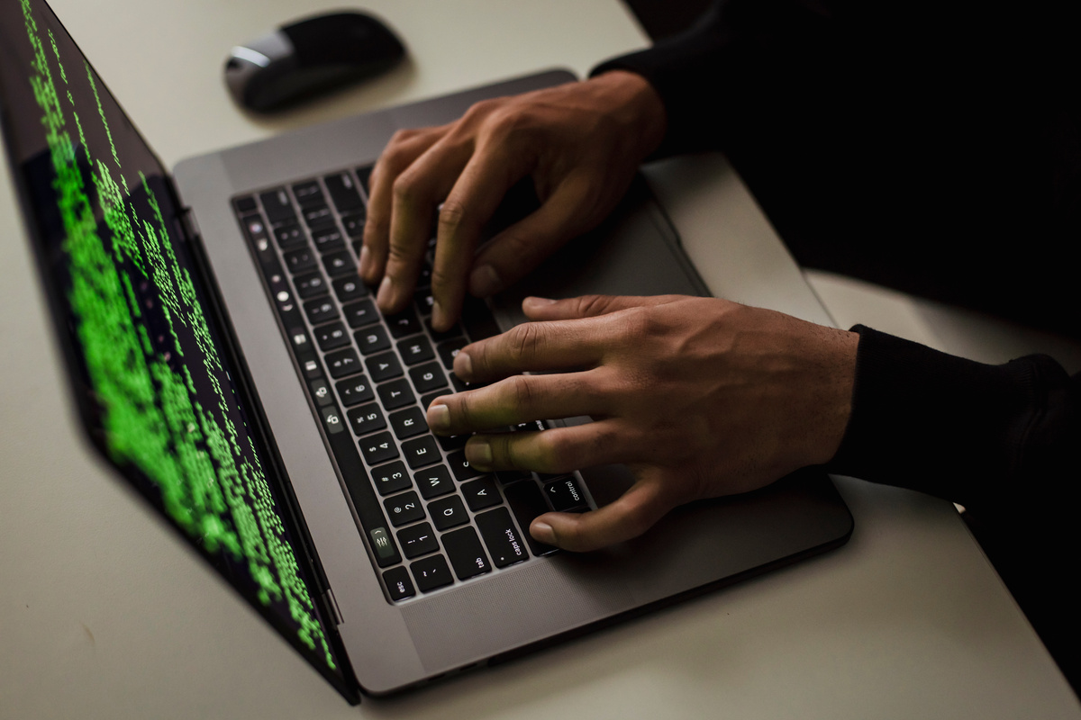 Crop cyber spy hacking system while typing on laptop